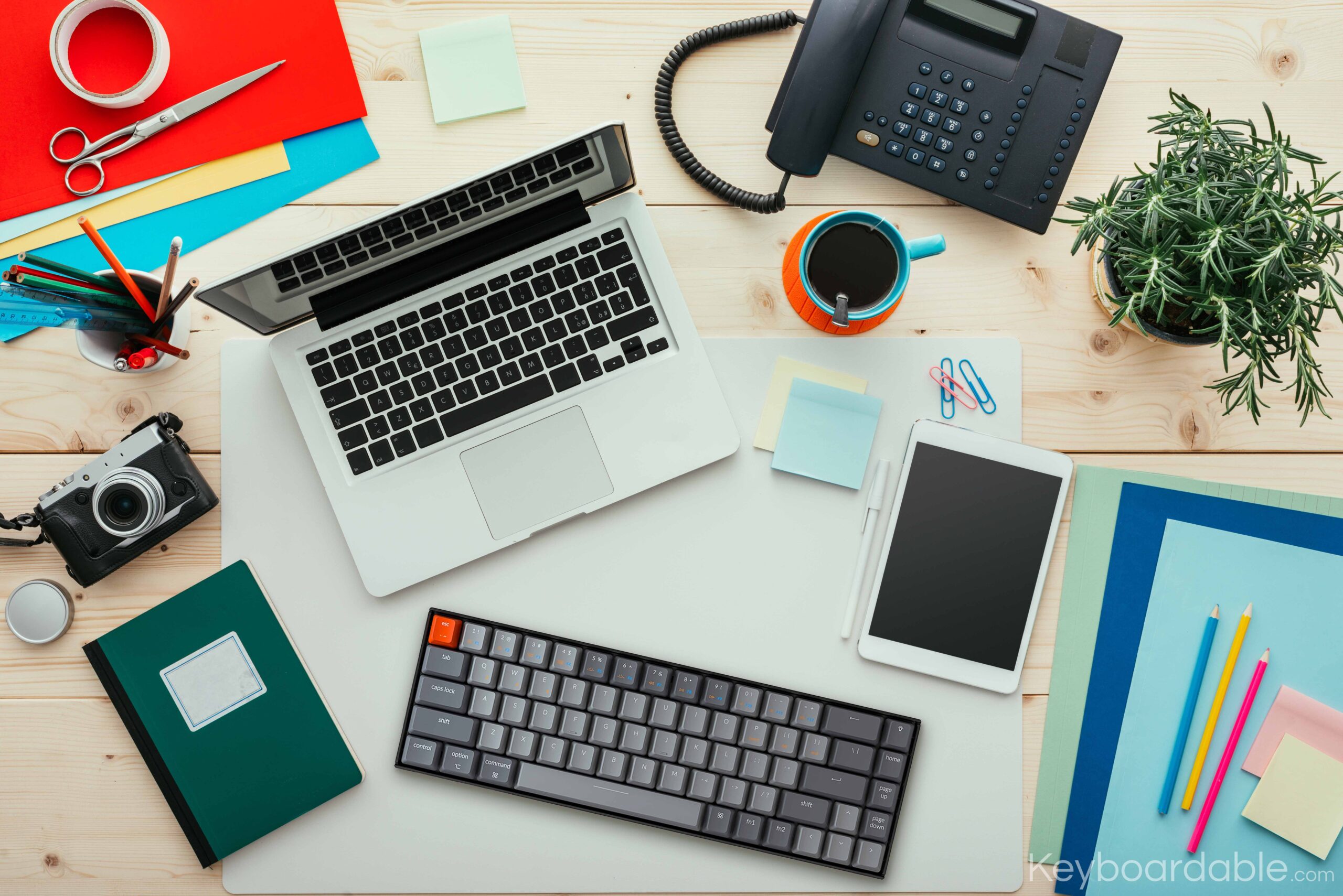 A laptop with an external keyboard, along with other desk items.